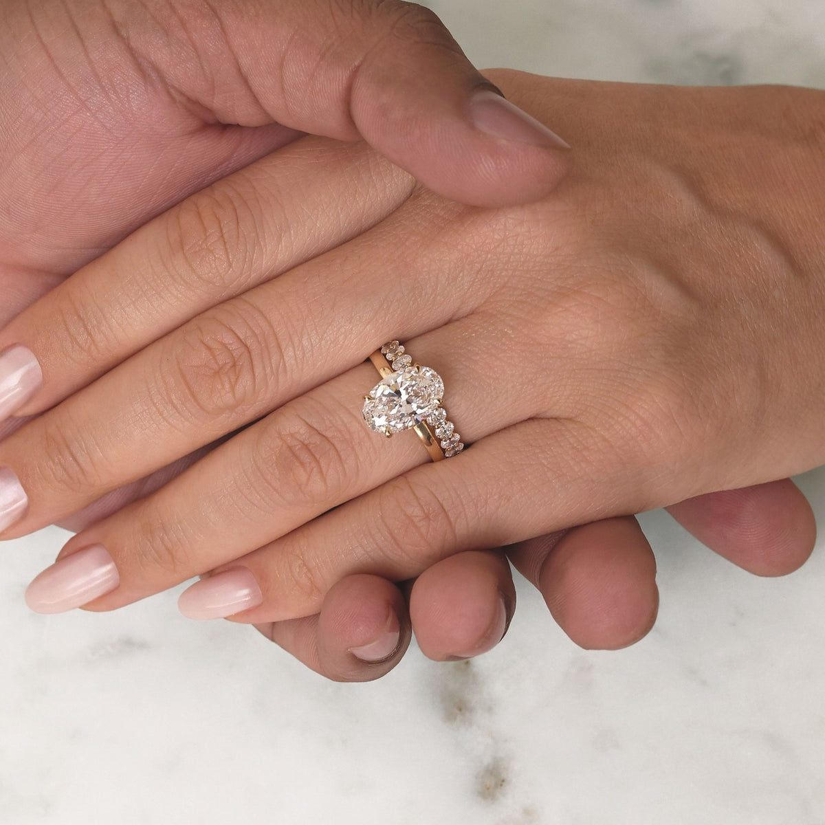Custom oval diamond engagement ring with matching wedding band in yellow gold by BYORO Dubai